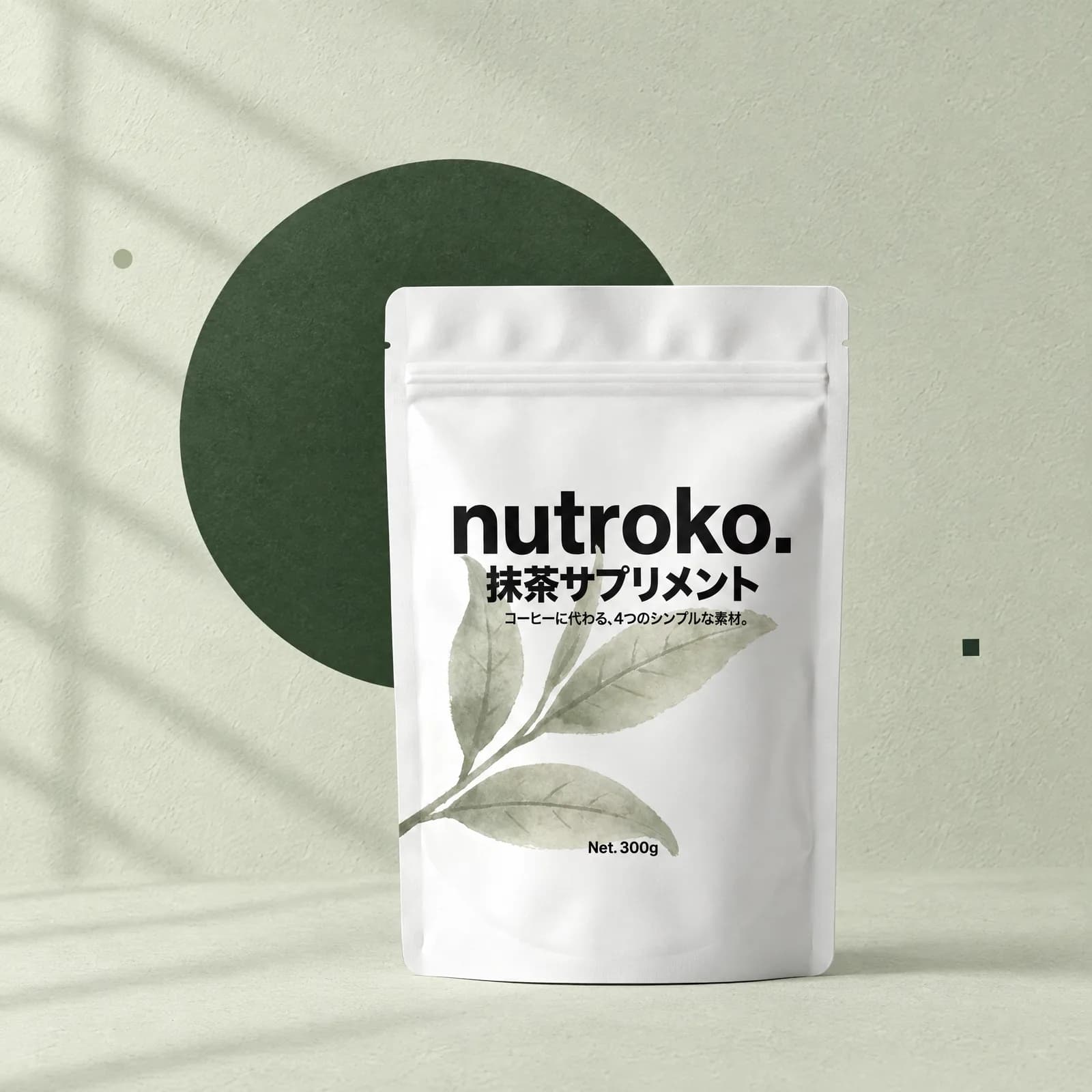 The white Nutroko pouch against a pale sage wall and a deep matcha-green round disc