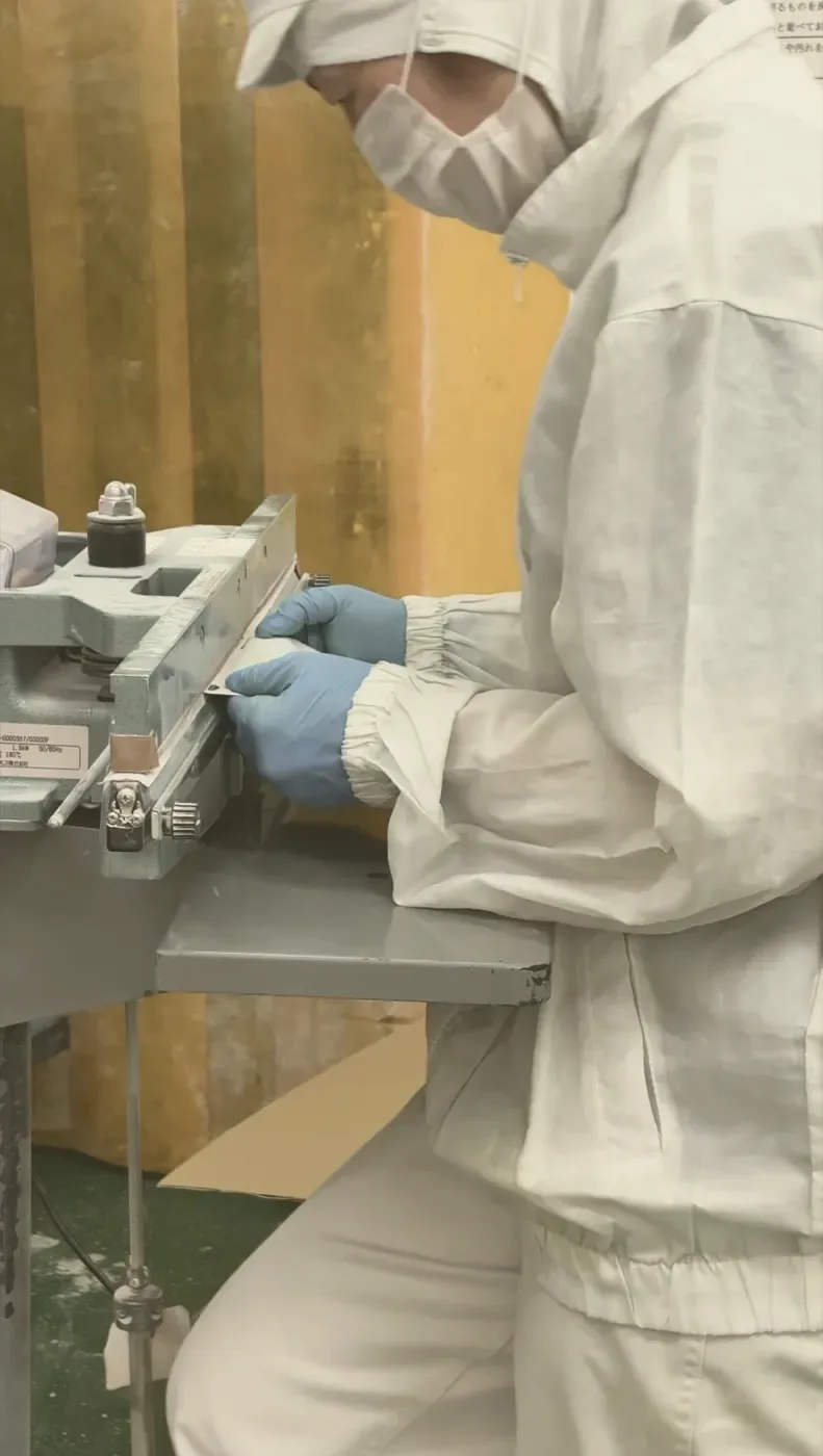 Gloved hands guiding a filled pouch through the bench heat-sealer