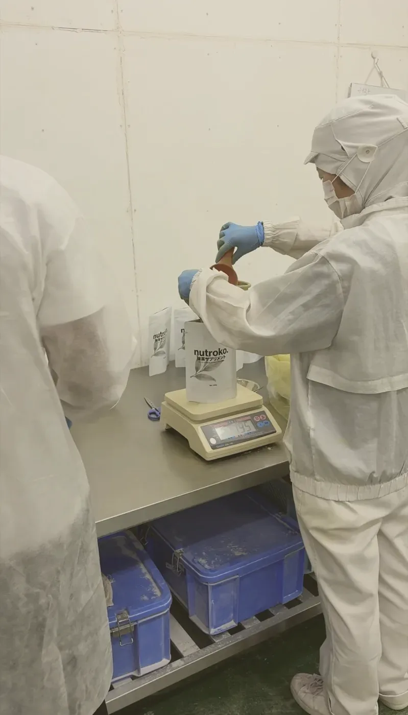 Pouring powder into a Nutroko pouch standing on the bench scale, one scoop at a time