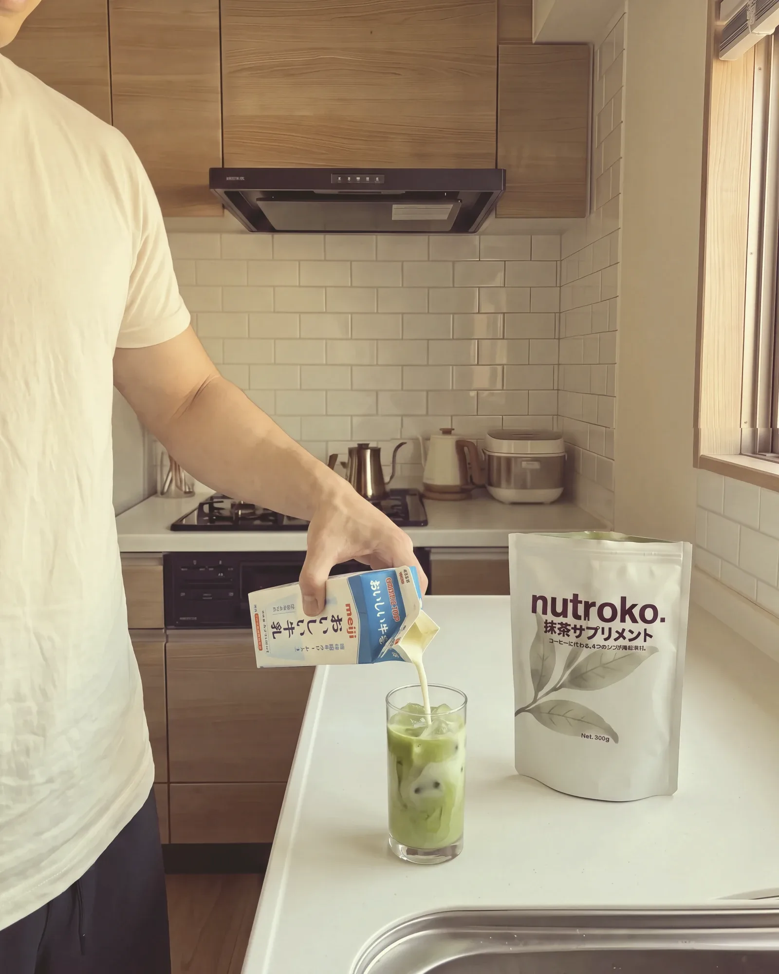Pouring milk from a Japanese milk carton into an ice-filled glass of green matcha